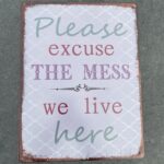 Tekstbord: “Please excuse the mess, we live here”, Metaal