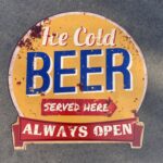 Tekstbord: “Ice cold beer served here, Always open”